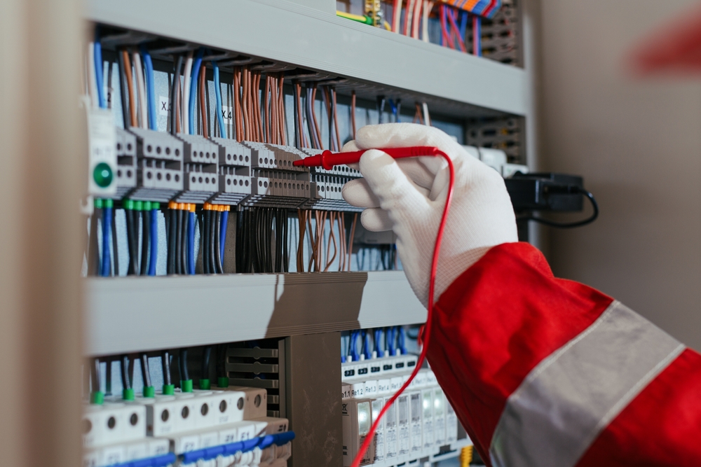 Photo of an electrical engineer using a digital multimeter to check the electric current voltage.